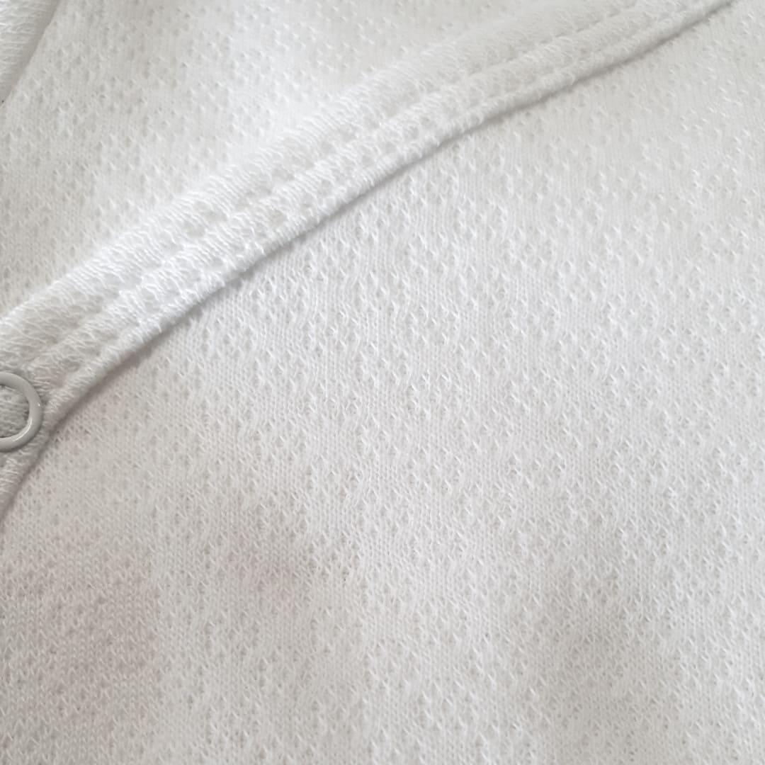 Malha branca de algodão para roupa de bebé, detalhe de textura e costura delicada.