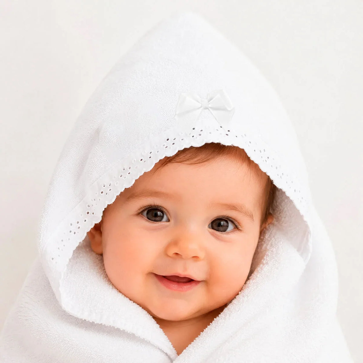 Bebê envolto em toalha branca com capuz e laço, ideal para recém-nascidos