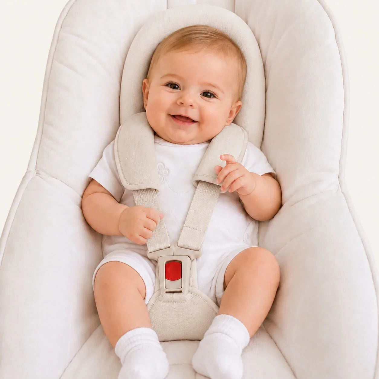 Bebê sorridente em cadeira de bebê com roupa branca e meias, conforto e segurança para recém-nascidos
