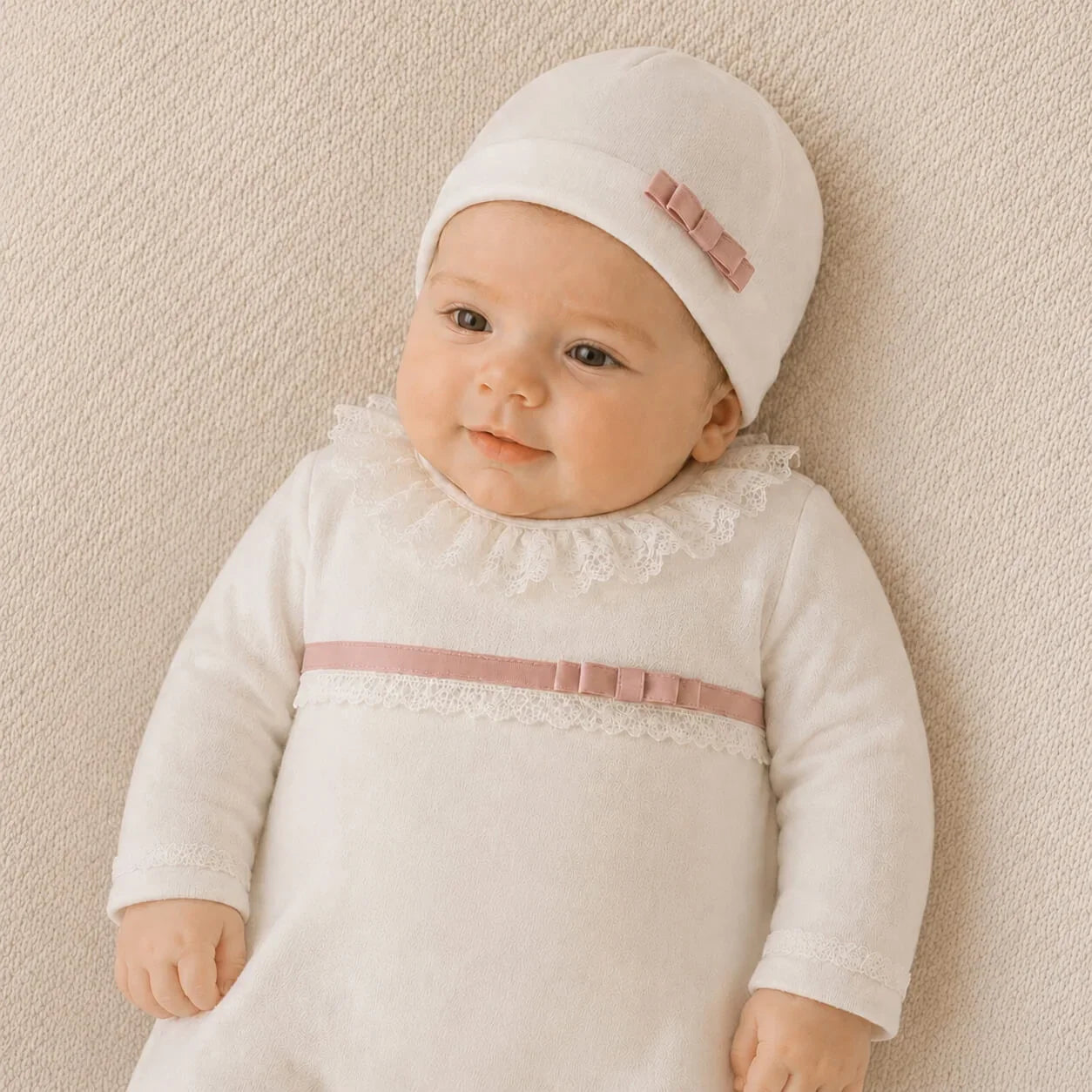 bebé usando roupa branca com detalhes em rosa e laço, ideal para recém-nascidos