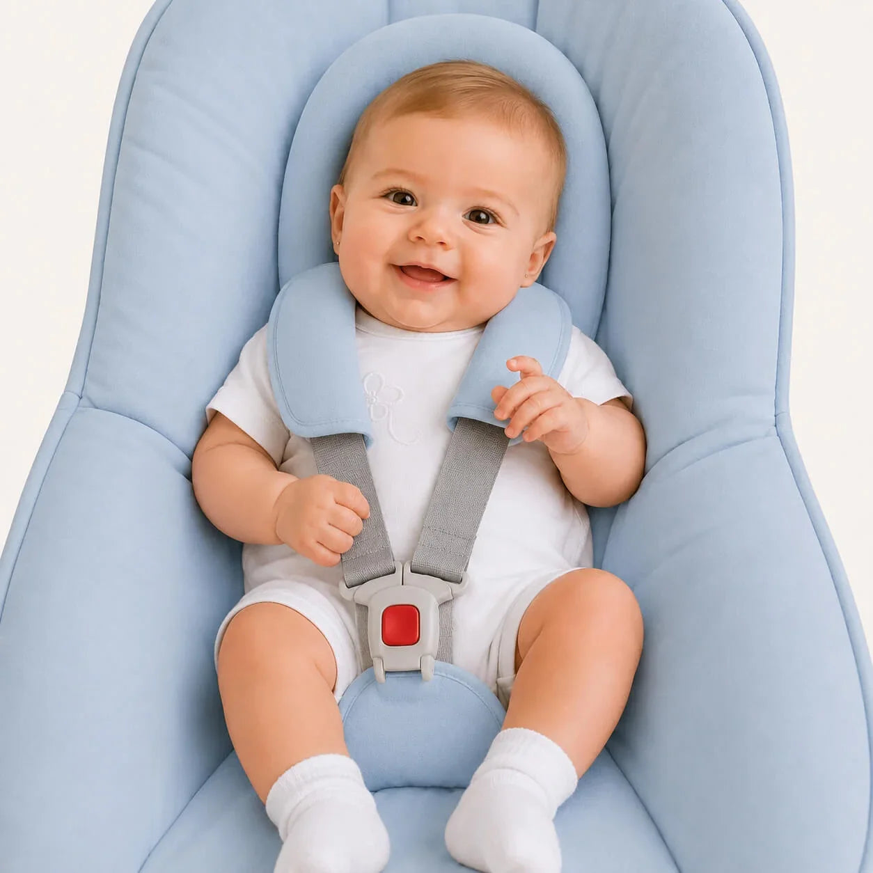Bebé sorridente em cadeira azul com cinto de segurança, roupa branca e meias, ideal para recém-nascidos