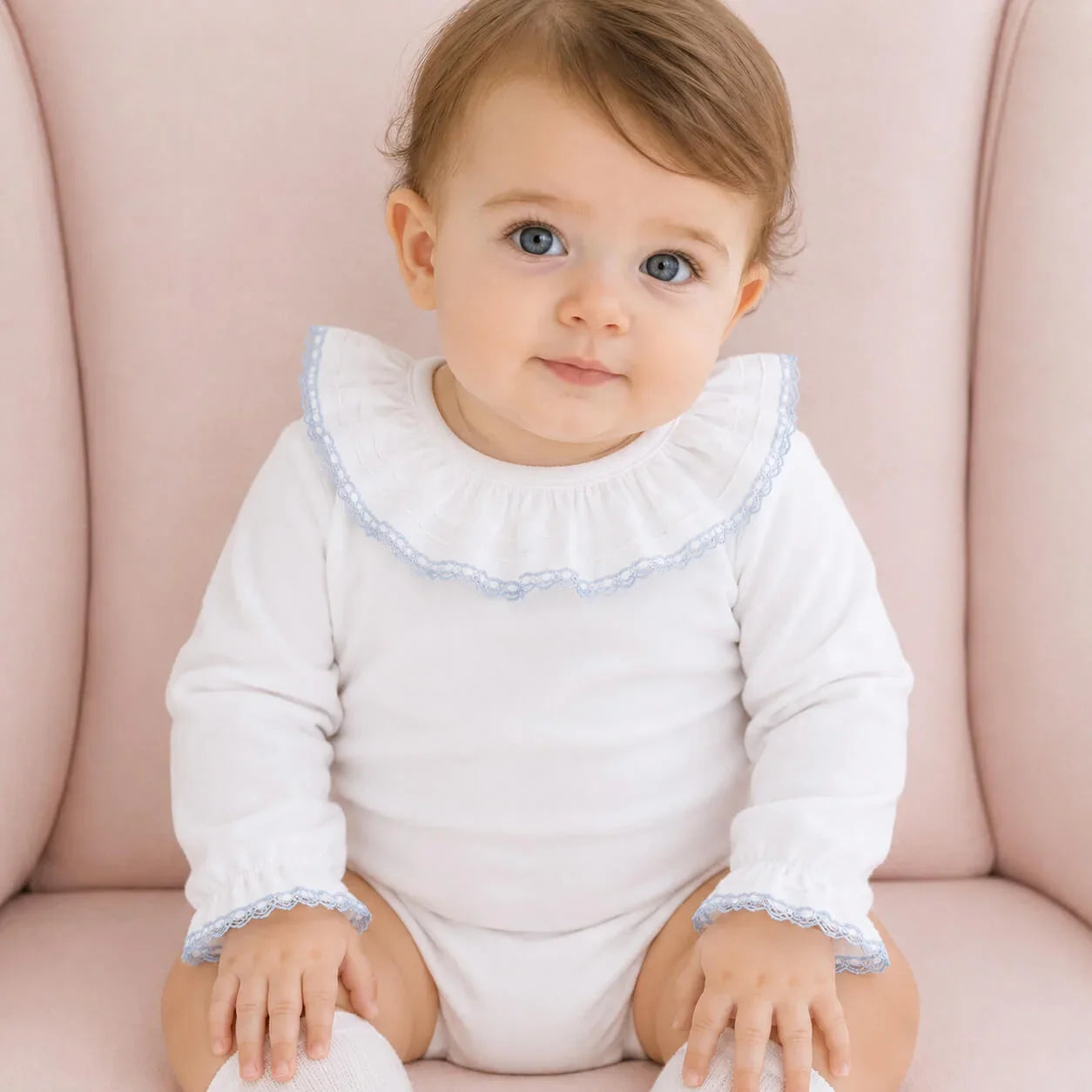 Bebê usando body branco com detalhes em renda azul, confortável e delicado para recém-nascidos.