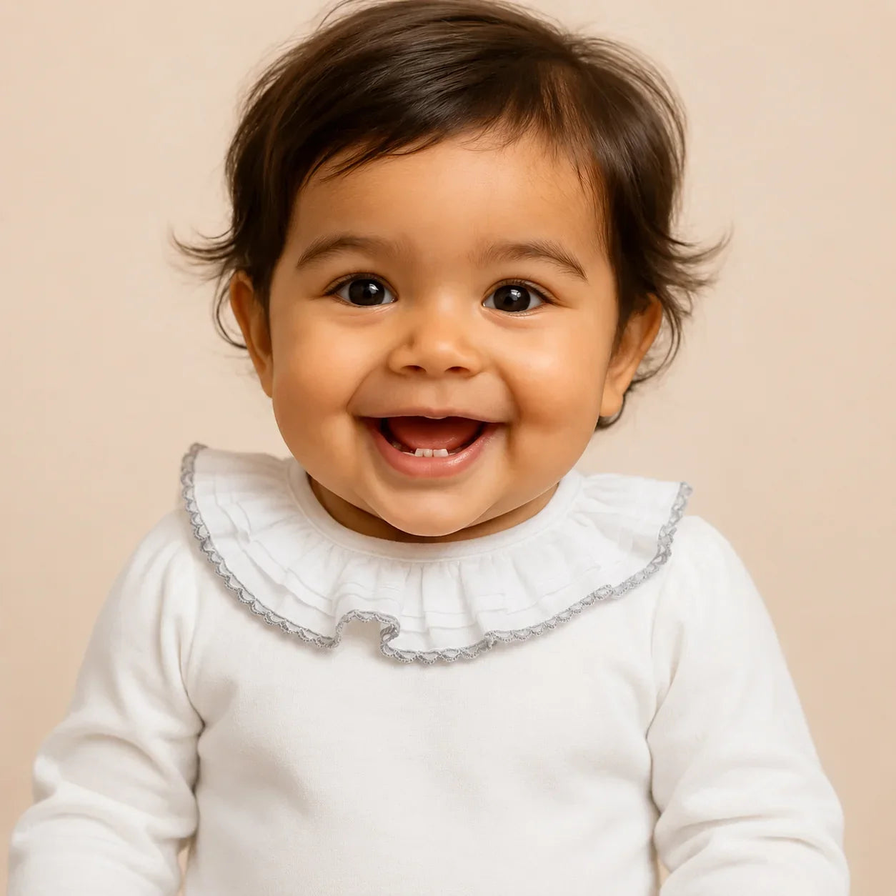 Bebê sorridente com roupa branca e babador franzido, roupa de bebê confortável e delicada