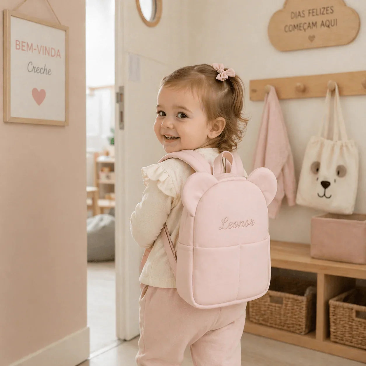 Menina sorridente com mochila rosa de orelhas, pronta para creche, ambiente acolhedor infantil