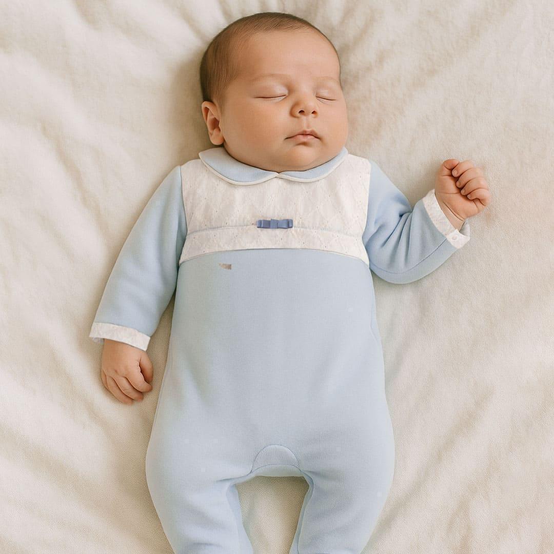 bebê dormindo com macacão azul claro de manga longa e gola branca, roupa confortável para recém-nascido