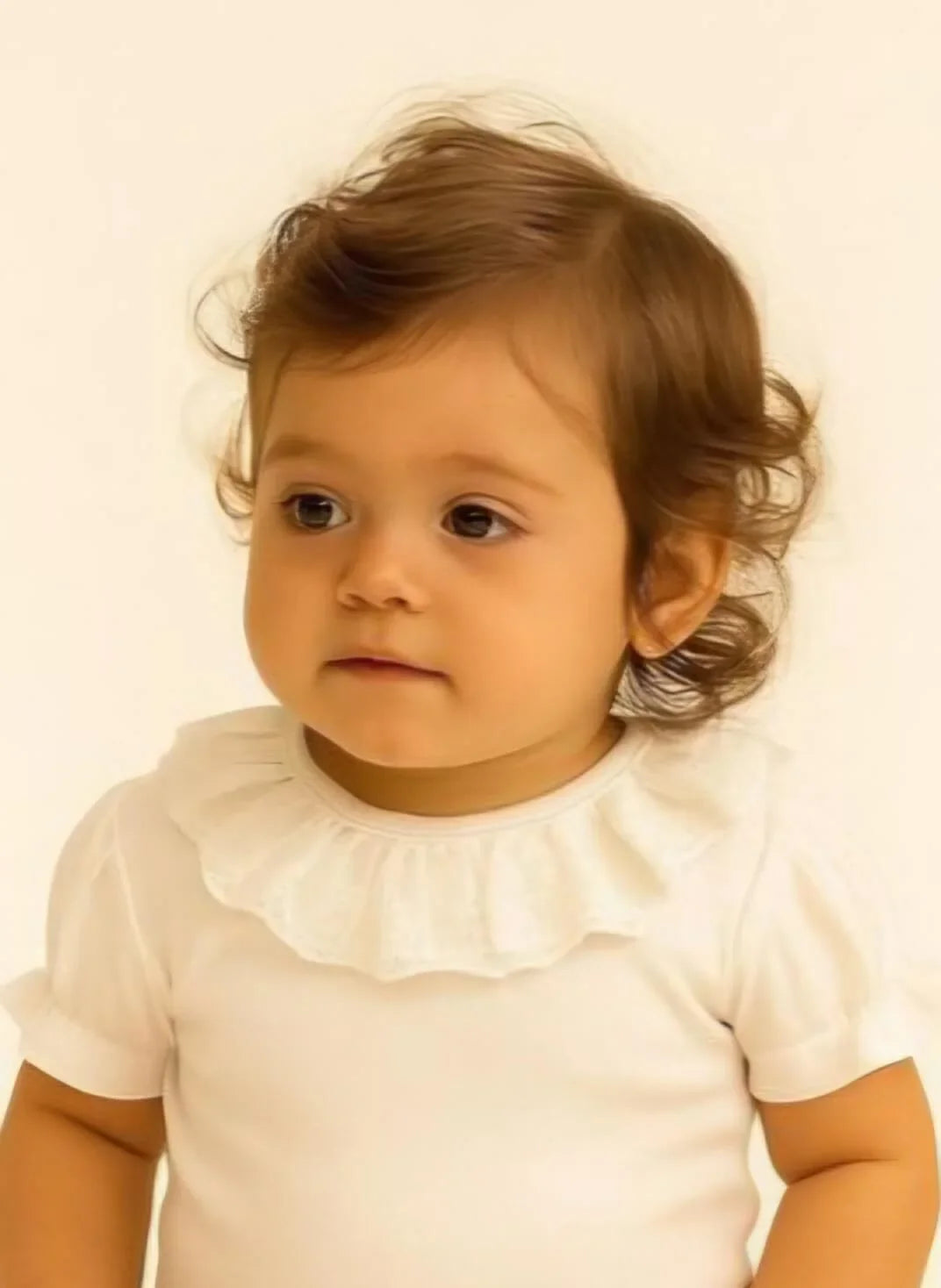 Bebê usando camiseta branca com babado, roupa confortável e delicada para recém-nascidos