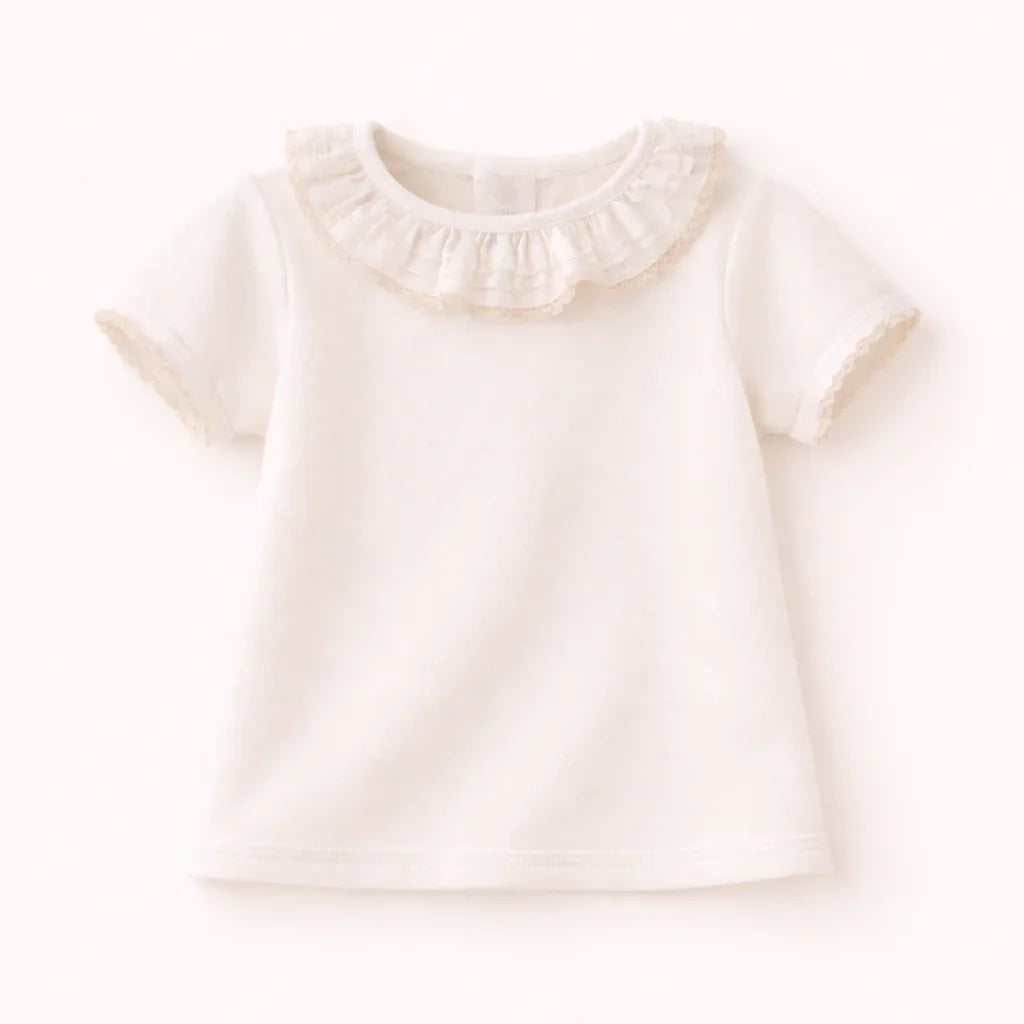 Camiseta de bebê branca com babados na gola, manga curta, feita em Portugal, confortável.