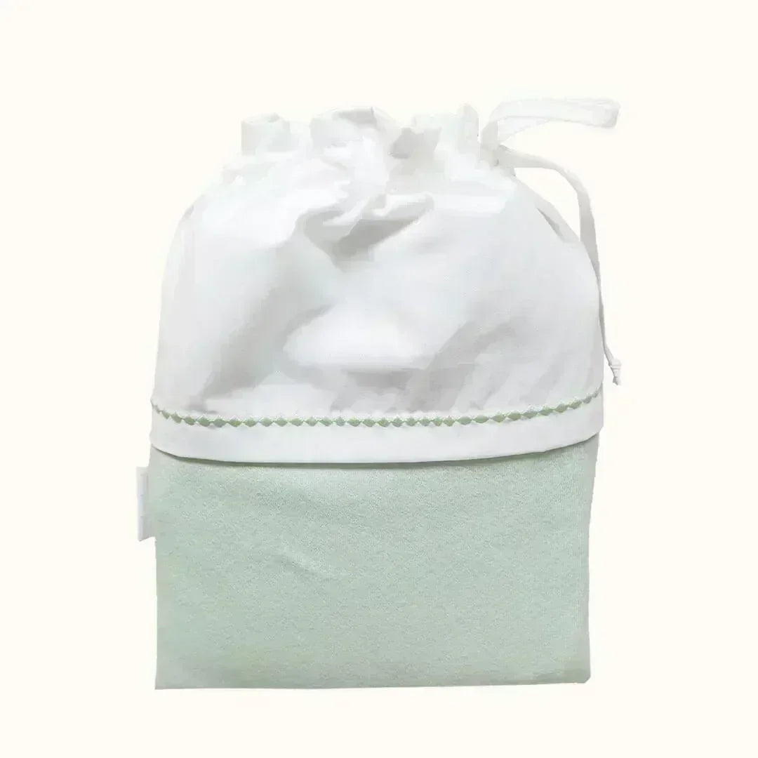 Saquinho para roupa de bebé em tecido branco e verde claro, com detalhe delicado e cordão de ajuste para guardar primeira roupa