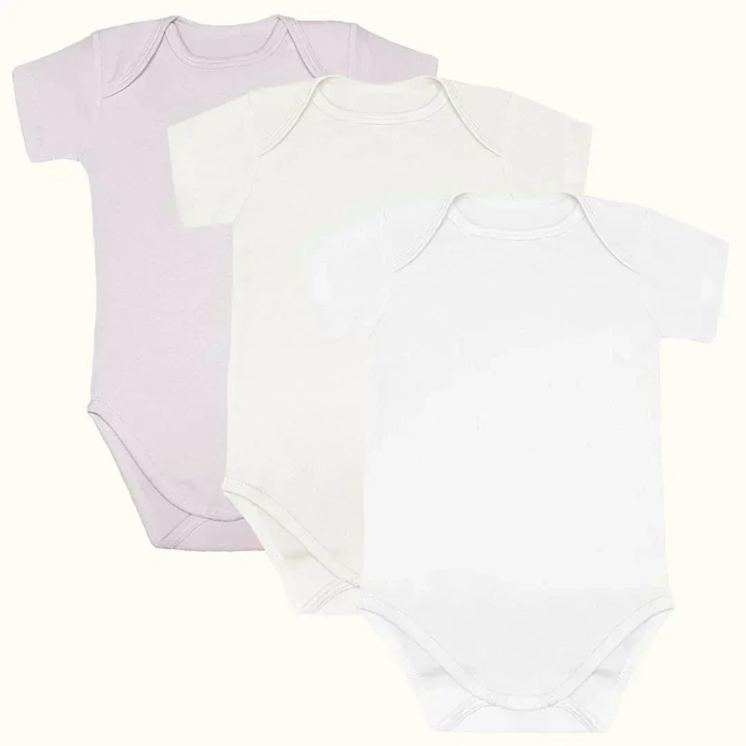 Kit com três bodies de bebê manga curta em tons claros, algodão confortável.
