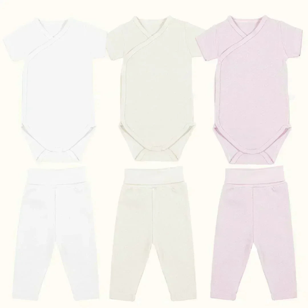 Kit com 3 bodies de manga curta e 3 calças sem pé para bebê, em tons branco, bege e rosa.