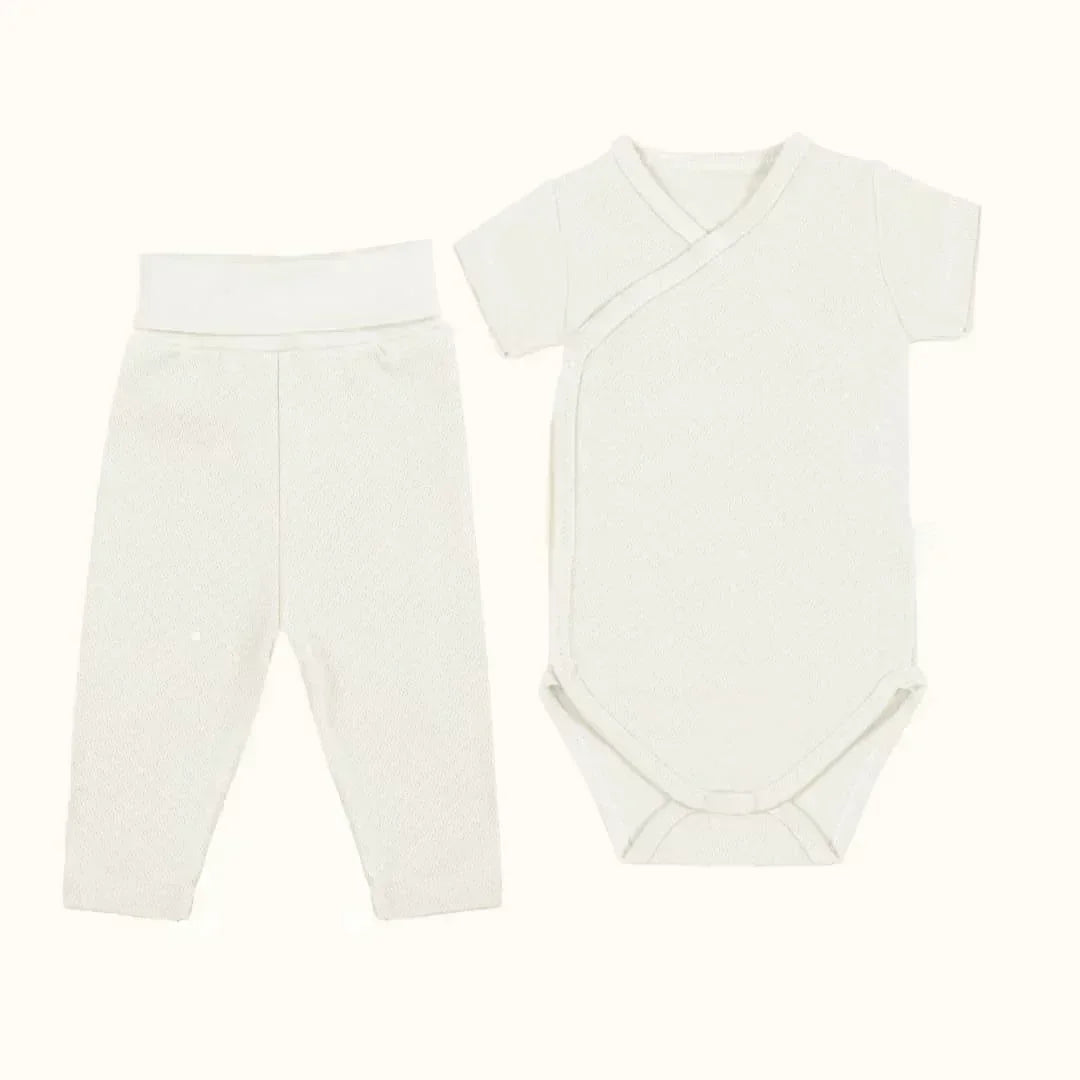 Conjunto roupa bebê unissex com body manga curta transpassado e calça sem pés, cor creme.
