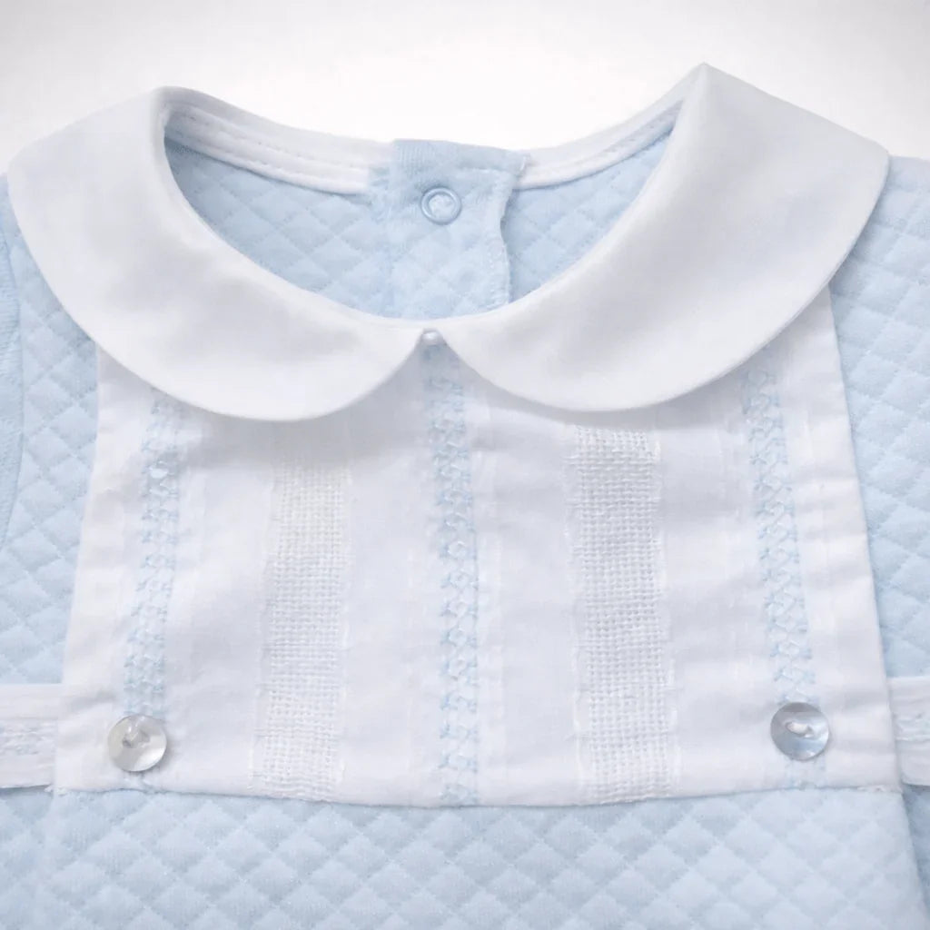 Babygrow azul claro de algodão para bebê, com gola branca e detalhes em renda e botões.