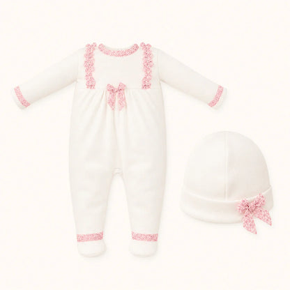 Conjunto de babygrow branco para bebé com detalhes rendados rosa e gorro combinando.