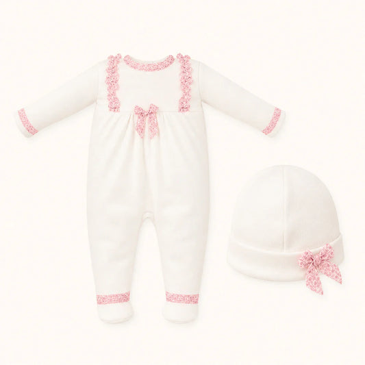 Conjunto de babygrow branco para bebé com detalhes rendados rosa e gorro combinando.