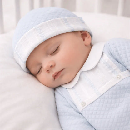 Bebê a dormir com babygrow azul claro e gorro, roupa confortável para recém-nascido.