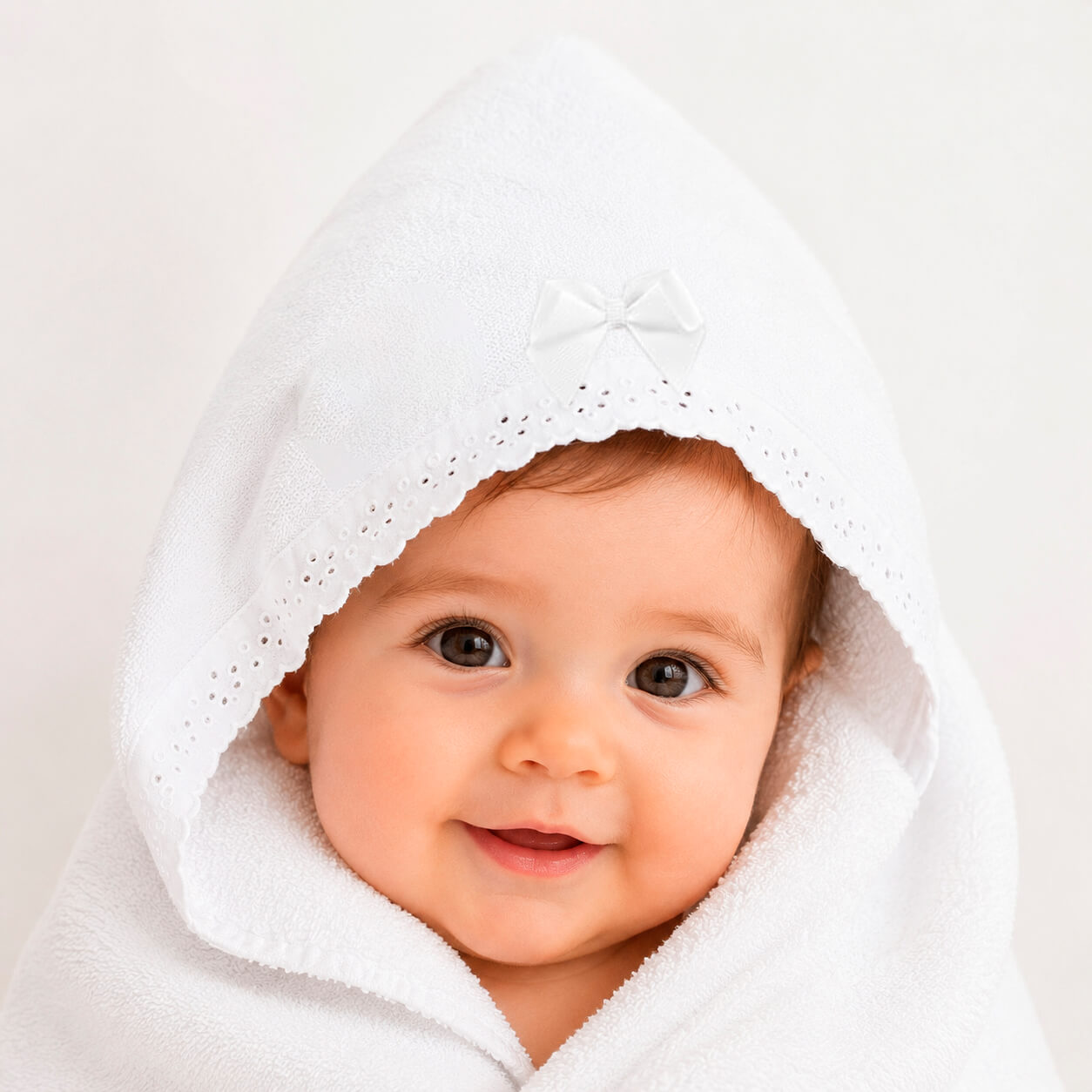 Bebê envolto em toalha branca com capuz e laço, ideal para recém-nascidos