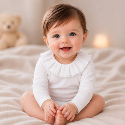 Bebe sorridente com body classic branco com gola em bordado inglês, manga comprida, tudo em algodão
