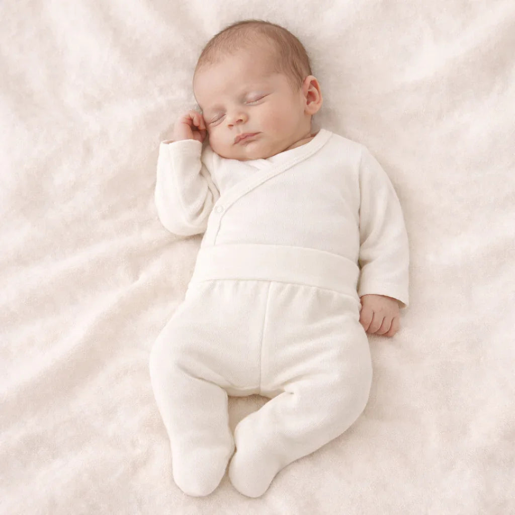 Bebê dormindo com body cruzado e calça beige, roupa confortável para recém-nascido