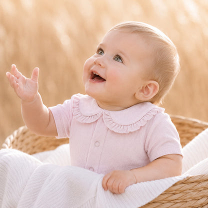 bebé sorridente vestido com body de gola em folho em malha algodão macio e fresco rosa, manga curta, ideal para os dias mais quentes