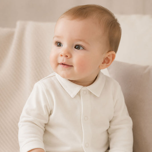 Bebé a sorrir vestido com camisola de gola de bico e apertar à frente com molas em bege