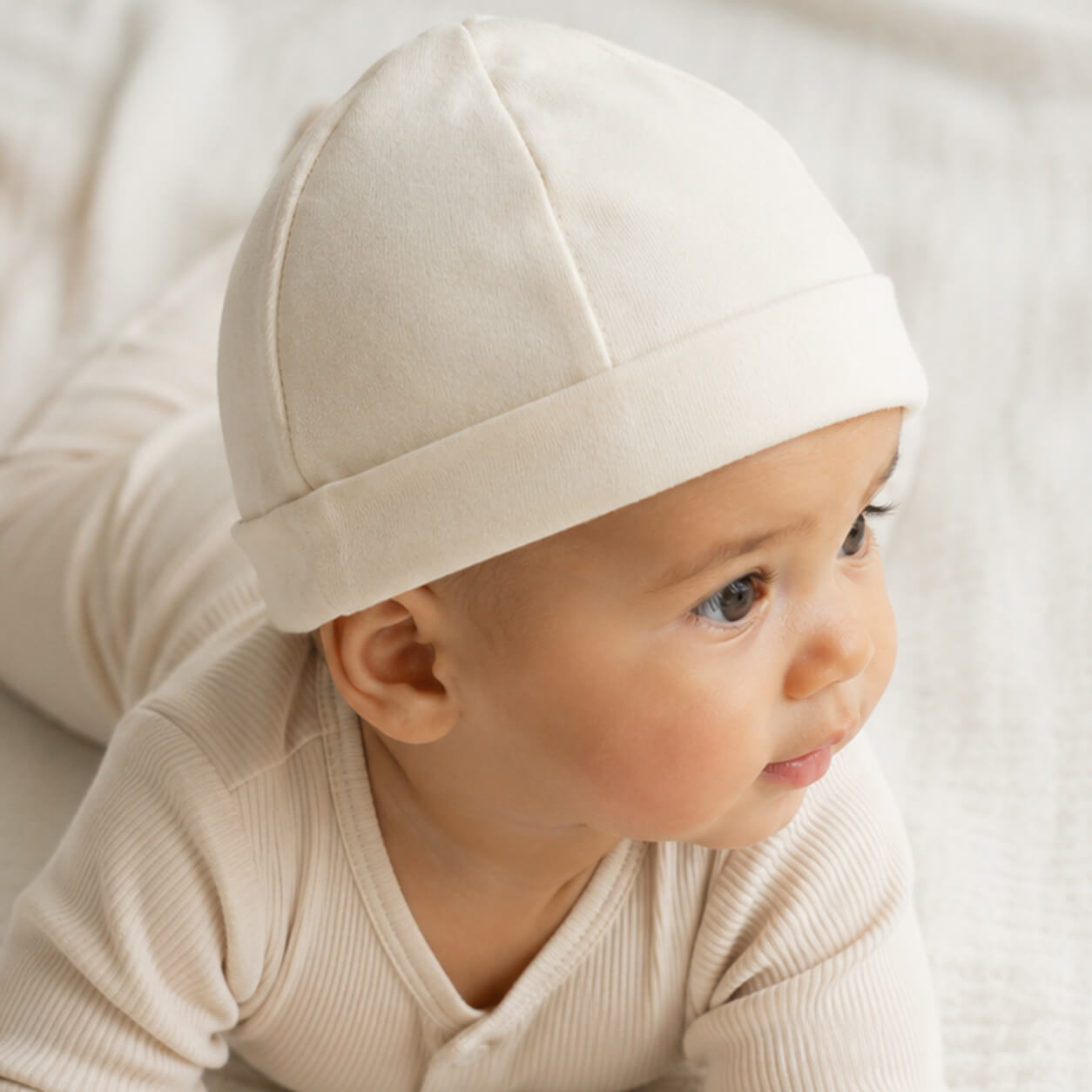 Bebê usando gorro e roupa de bebê macia, ideal para recém-nascidos com pele delicada
