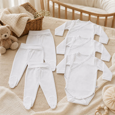 conjunto de 3 bodies cruzados e 3 calças sobre uma mesa, indispensáveis para os bebés
