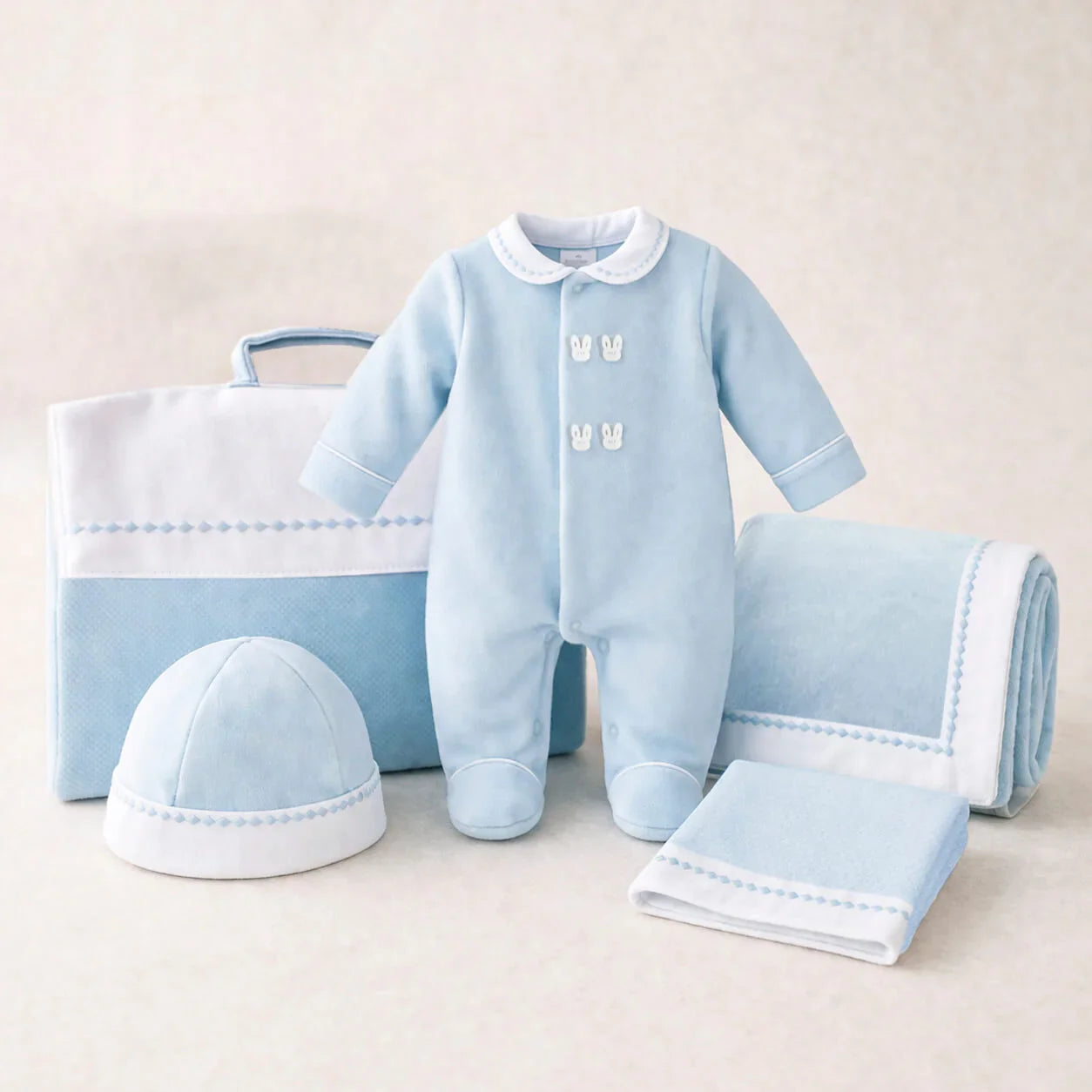 Conjunto de roupa azul para bebé com macacão, touca, manta e acessórios em algodão.