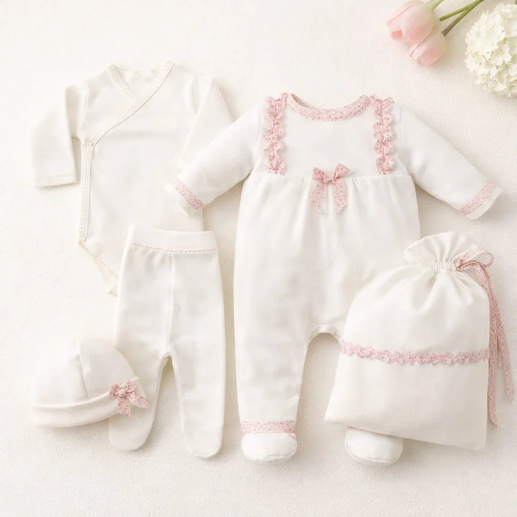 Conjunto de roupa de bebé recém-nascido branco com detalhes rosa, inclui body, calça, gorro, saco e macacão.