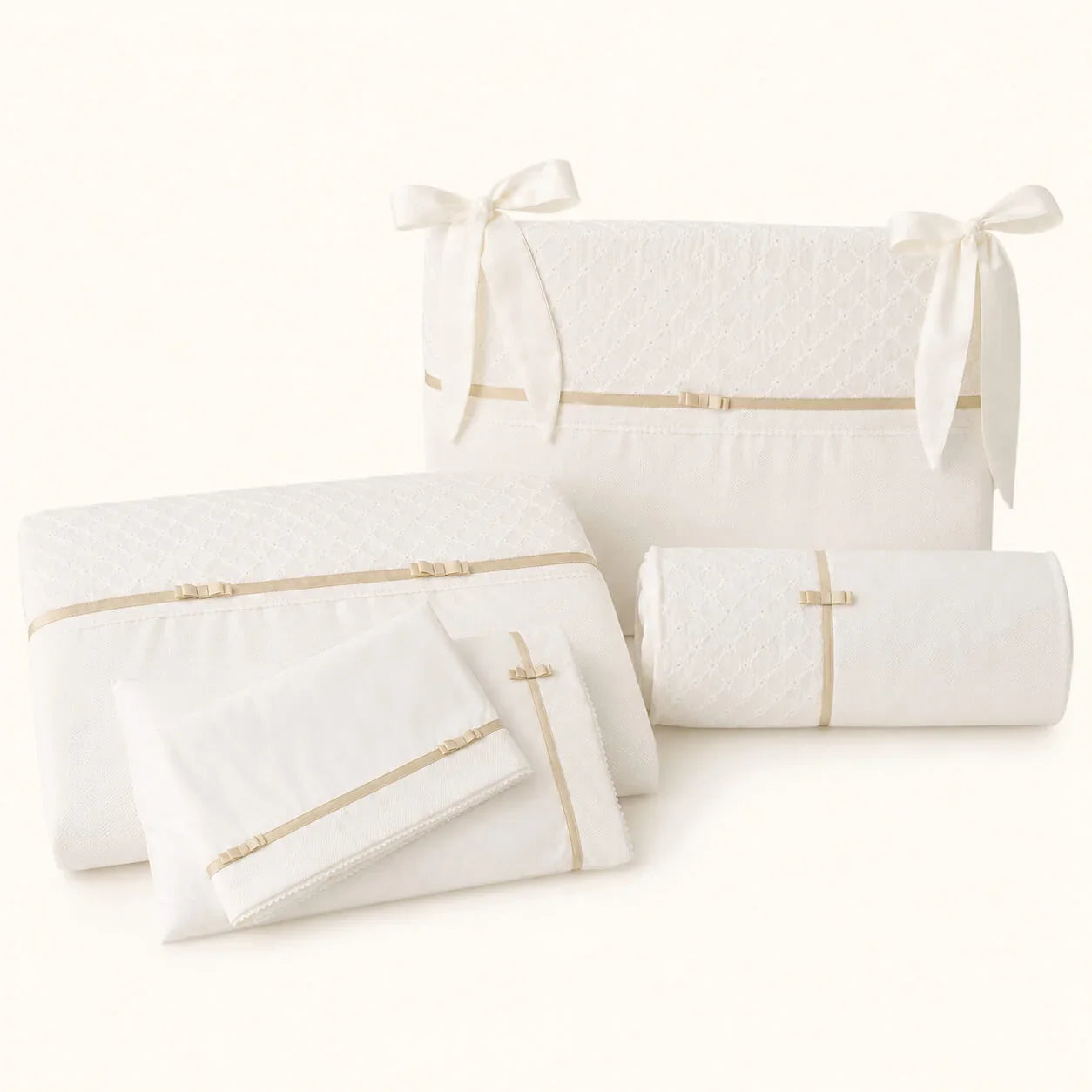 Roupa de Berço de bebé bege com detalhes dourados e laços composto por edredão,  resguardo para as grades, lençóis e travesseiro decorativo