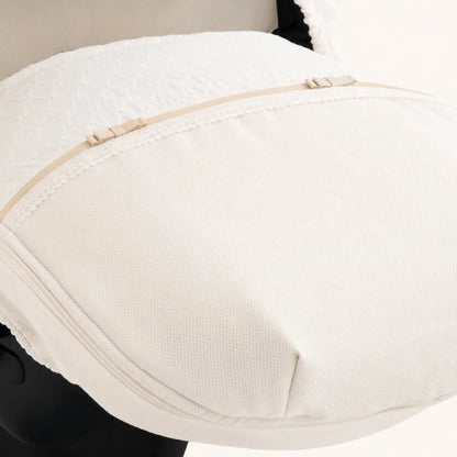 Detalhe da frente da babycoque em piquet bege e tecido bordado inglês, rematado com renda bege, fita e Laços bege dourado