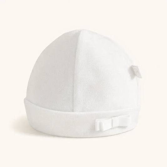 Gorro de bebé branco em algodão com laço pequeno aplicado, ideal para recém-nascidos.