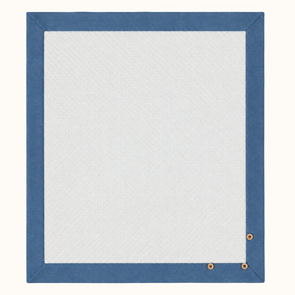 Manta rectangular para bebé em malha branca losango de algodão. Barras em denim azul à volta e 3 botões de madeira decorativos. Essencial para o berço