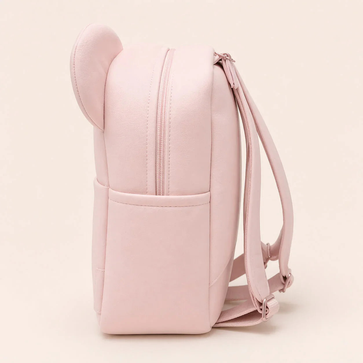 Mochila infantil rosa claro com orelhas, vista lateral, alças ajustáveis, design delicado.
