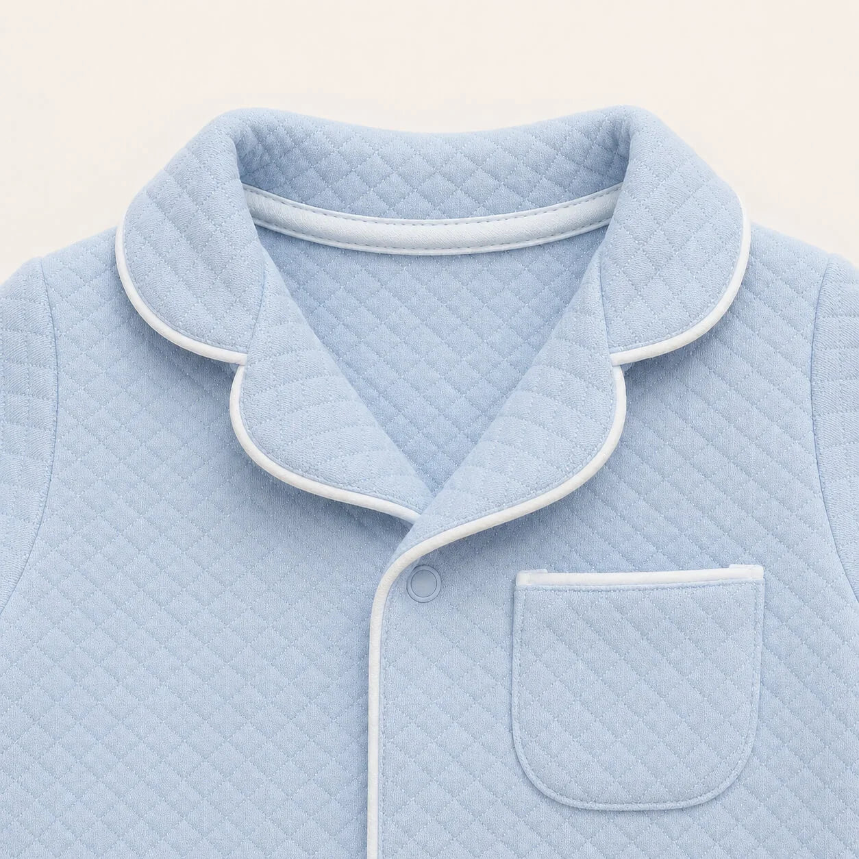 Pormenor do babygrow em malha azul com pormenor branco inspirado nas camisas de homem 