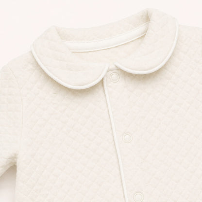 Pormenor da gola redonda com vivo branco do babygrow prestige em bege. Tudo muito delicado a pensar na pele sensível do bebé 