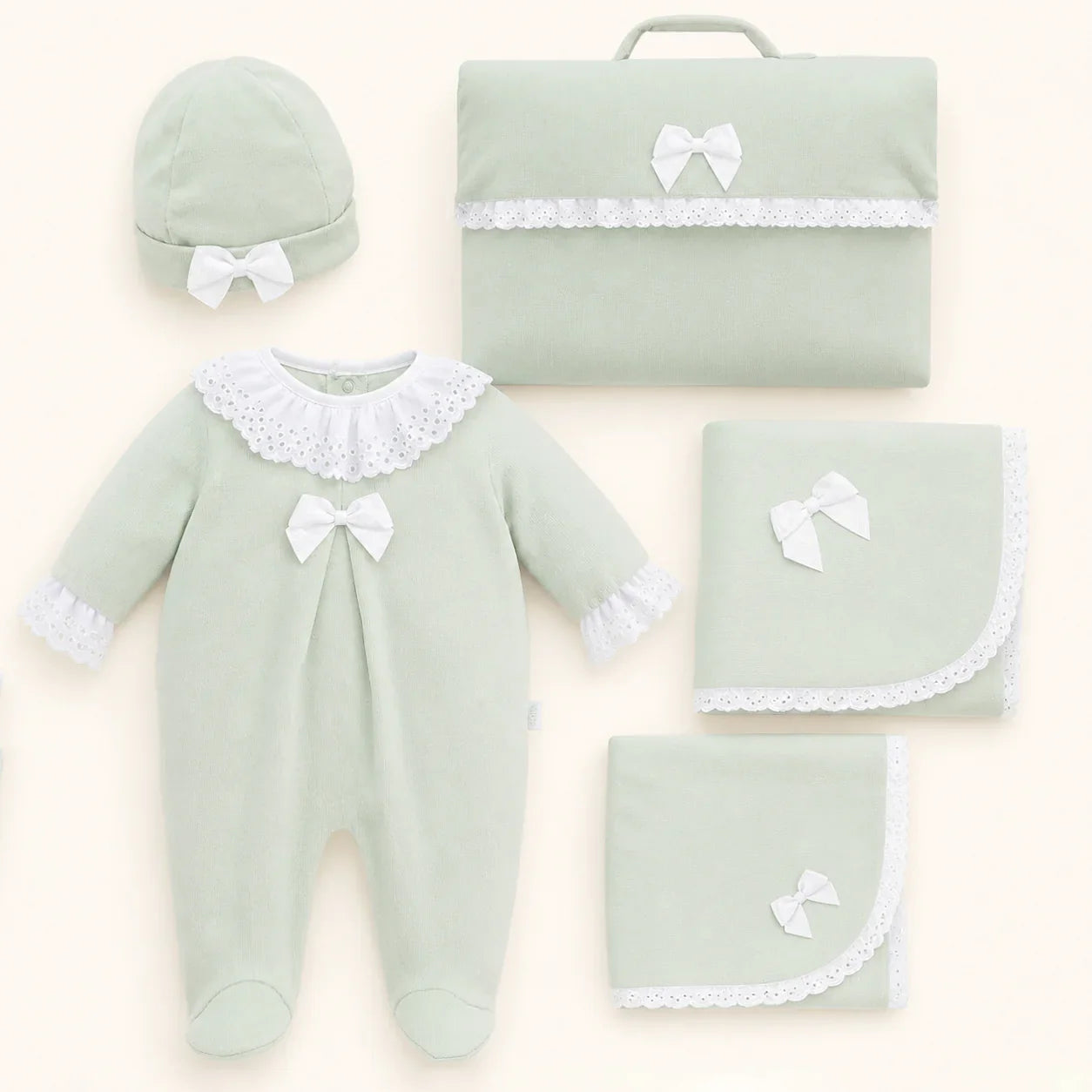 Conjunto de enxoval de bebê verde claro com renda branca, incluindo macacão, touca e mantas.