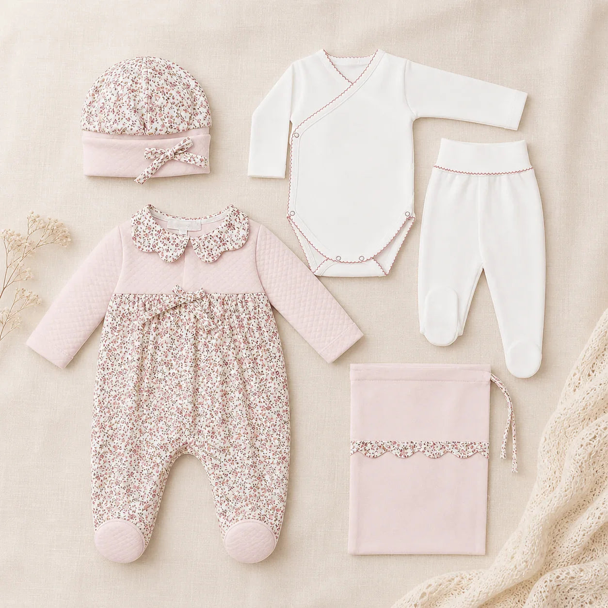 Conjunto enxoval de bebé rosa com body, calça, gorro, saco e babygrow floral, tecido delicado.