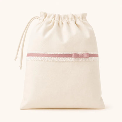 Saco de malha bege com laço rosa e renda, ideal para enxoval de bebé 