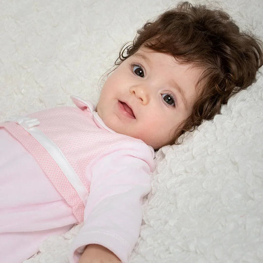 bebê deitado com babygrow rosa, roupa confortável para recém-nascidos, fundo branco macio