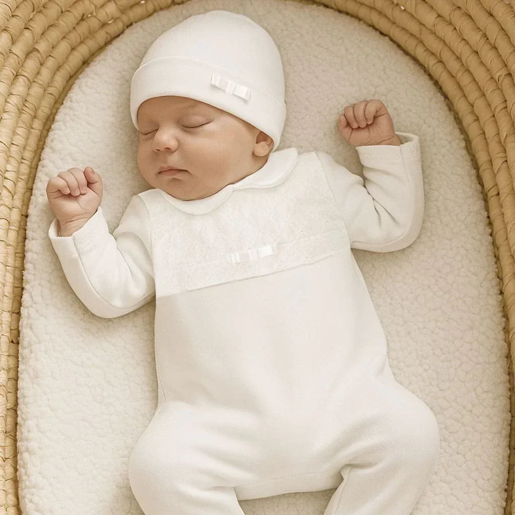 bebê dormindo em ninho, vestindo babygrow e gorro branco delicados, roupa confortável para recém-nascido