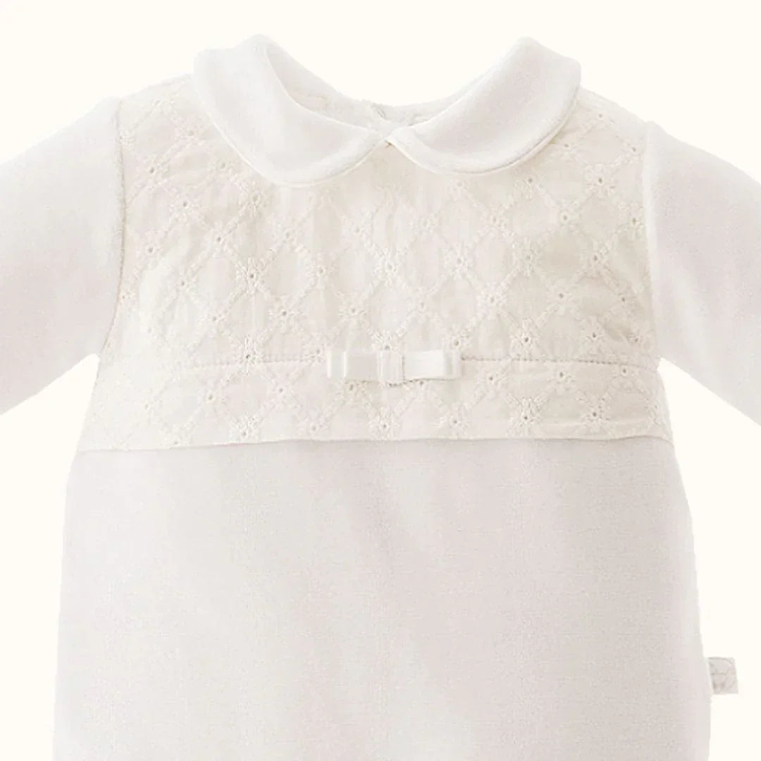 Babygrow branco de bebé com gola, renda delicada e laço decorativo na frente.