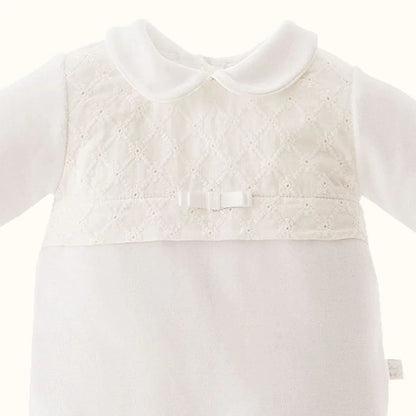 Babygrow branco de bebé com gola, renda delicada e laço decorativo na frente.