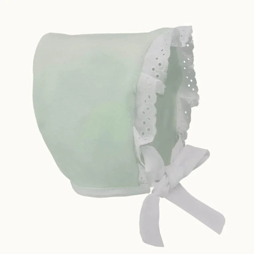 Touca de bebé verde claro com renda branca e laço, roupa confortável para recém-nascidos.