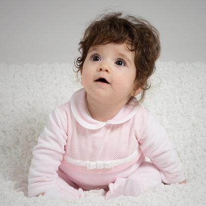 bebê sentado com babygrow rosa de manga comprida e laço, sobre manta branca, roupa confortável para recém-nascido