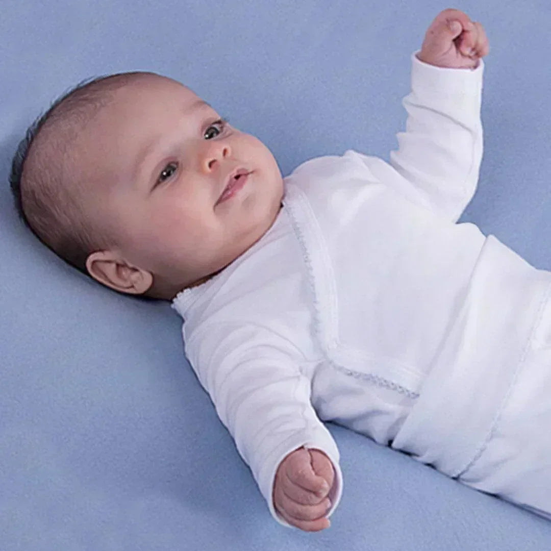 Bebê deitado em manta azul, usando body branco confortável para recém-nascido.