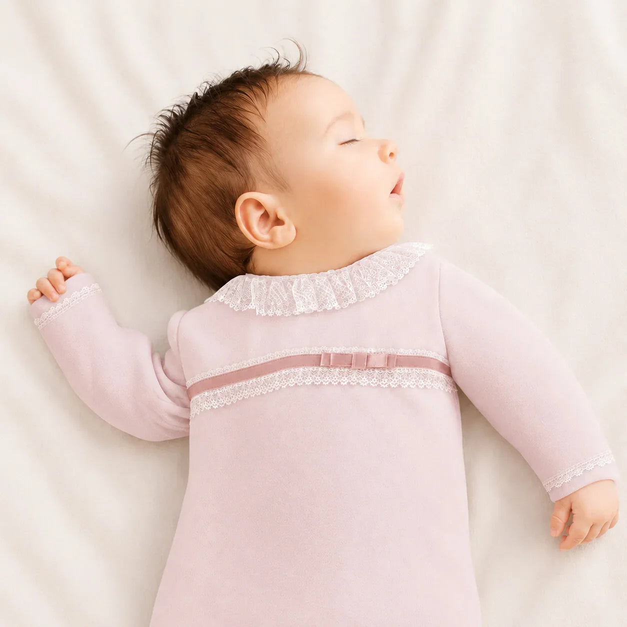 Bebê dormindo em roupa de bebê rosa com detalhes em renda, confortável e suave para recém-nascidos.