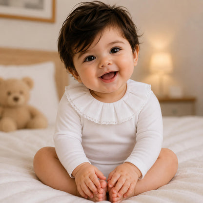 Bebe sorridente com body classic branco com gola em bordado inglês, manga comprida, tudo em algodão