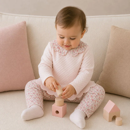 Bebê usando conjunto de 2 peças rosa com estampa floral, brincando com blocos de madeira