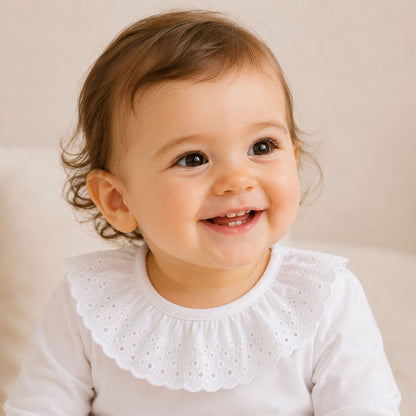 bebé  sorridente, vestida com body de gola bonny bordado inglês branco.