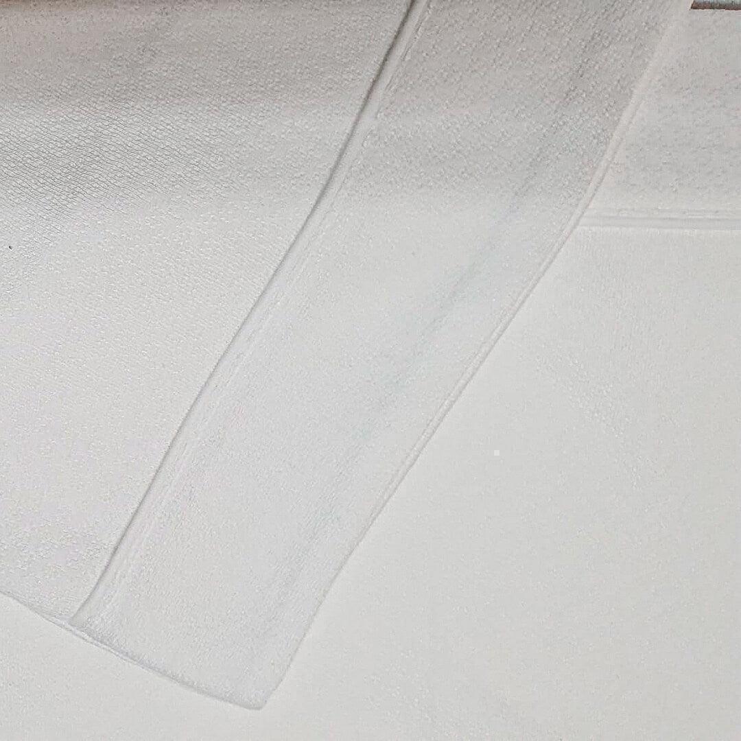 Conjunto de lençóis de malha branco em algodão para bebé, textura macia e confortável.
